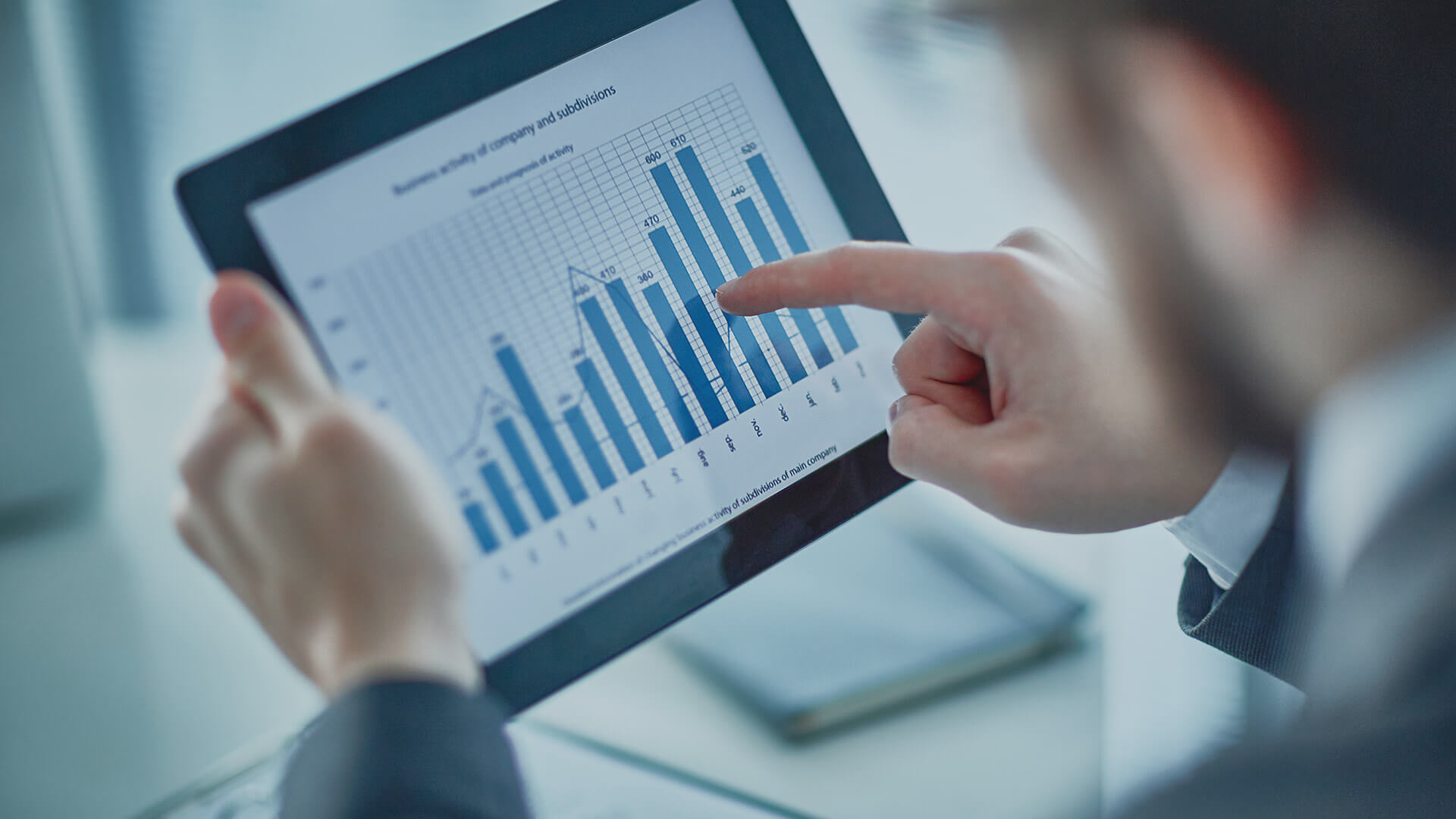 Analyzing business activity on a tablet with a bar graph showing company subdivisions.