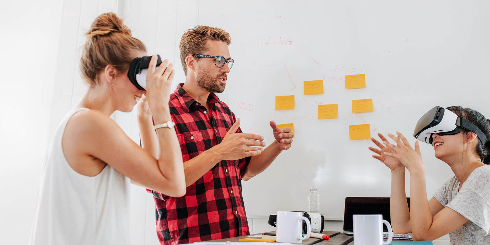Team brainstorming website ideas with VR headsets. Sticky notes on whiteboard.